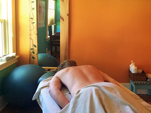 person on massage table in darkened room with natural light